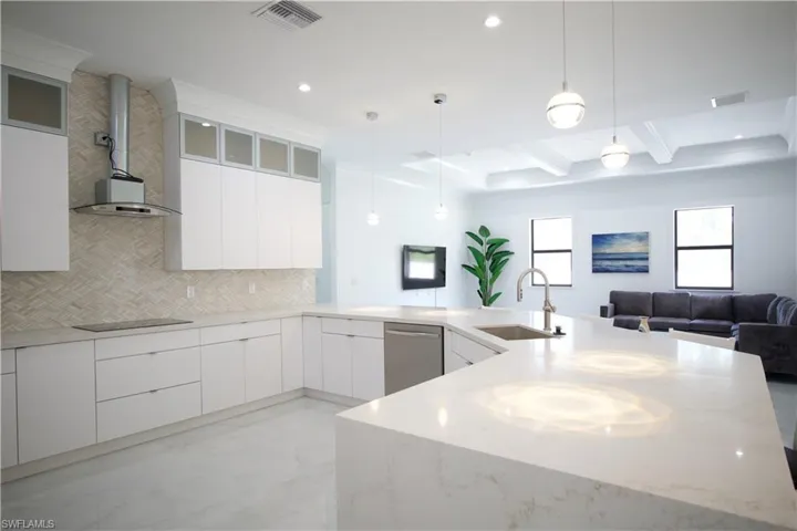 Kitchen with beamed ceiling, dishwasher, pendant lighting, backsplash, and sink