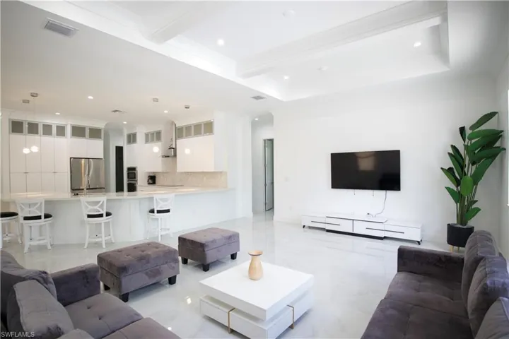 Tiled living room featuring beamed ceiling and a raised ceiling