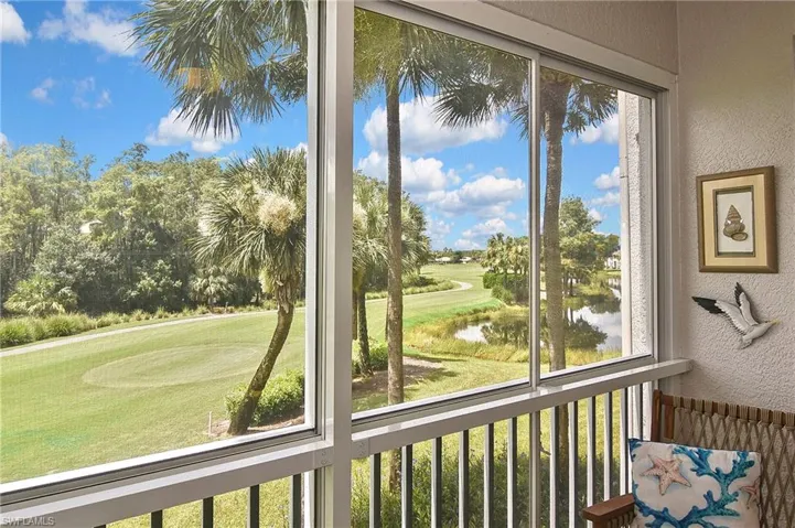 Sunroom / solarium featuring view of golf course and a water view