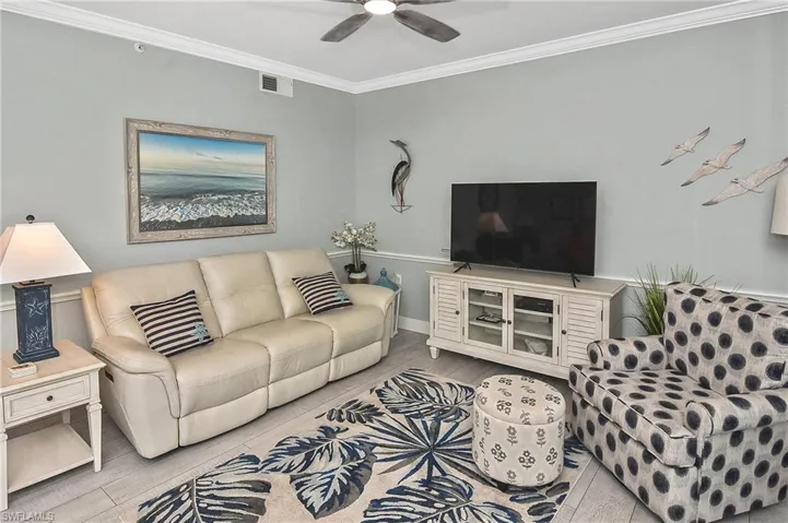 Living area with crown molding, a ceiling fan, and wood finished floors