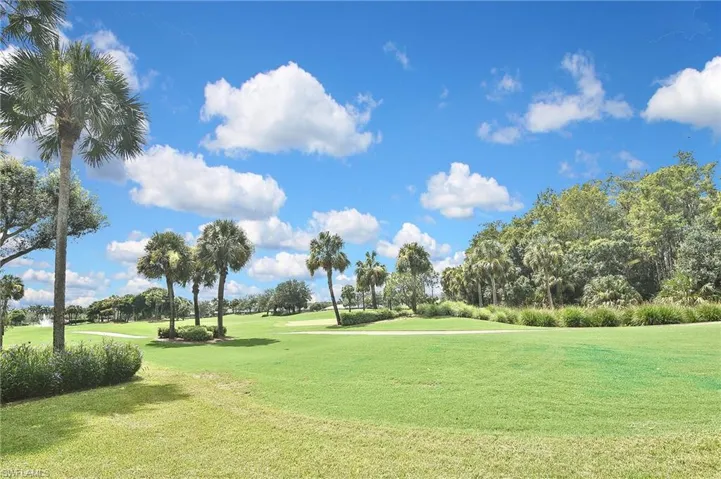 View of community with a lawn, view of golf course, and view of scattered trees