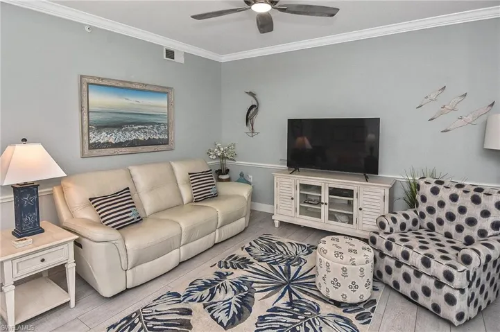 Living room featuring ornamental molding, a ceiling fan, and light wood-style flooring