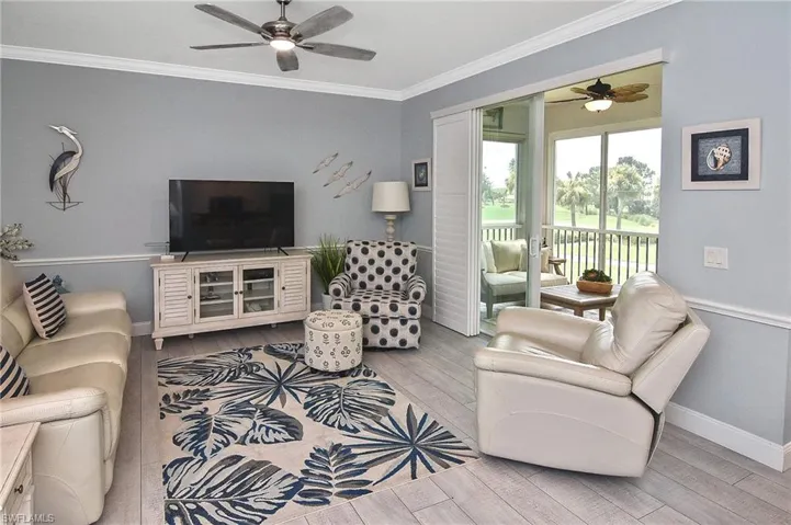 Living area with ceiling fan, crown molding, and light wood-type flooring