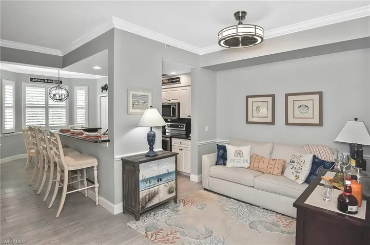 Living room with crown molding, light wood-type flooring, and a chandelier