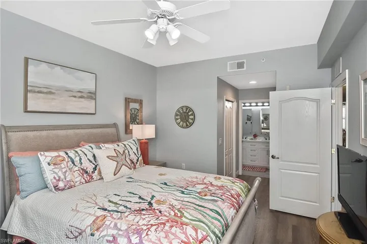 Bedroom featuring dark wood finished floors, ensuite bath, and ceiling fan