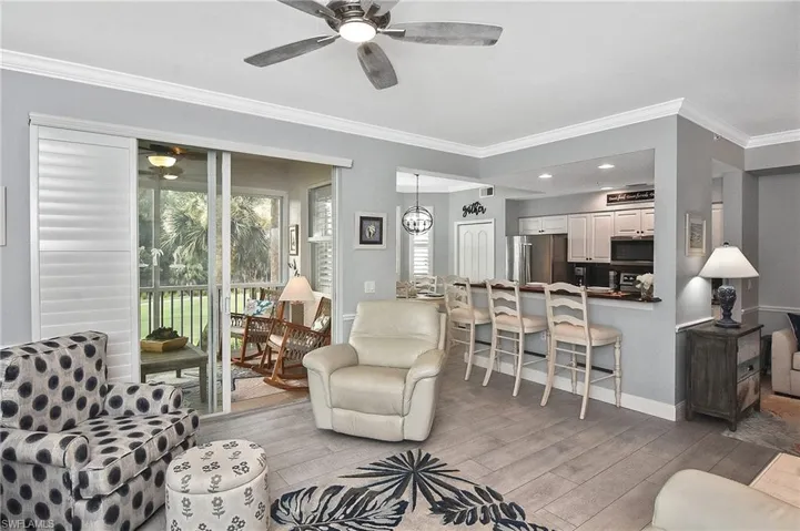 Living room featuring ceiling fan, ornamental molding, and light wood-style flooring
