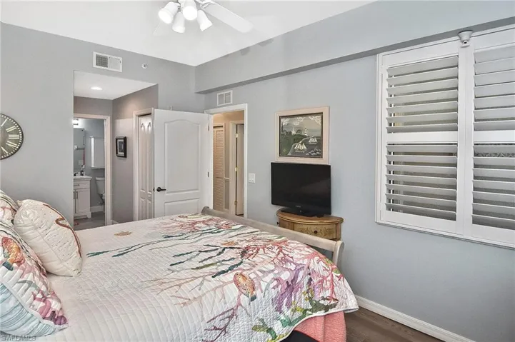 Bedroom featuring wood finished floors, ensuite bathroom, and ceiling fan