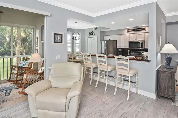 Kitchen featuring plenty of natural light, crown molding, a kitchen bar, light wood-type flooring, and a peninsula