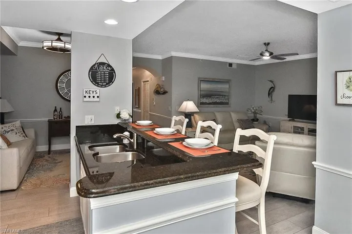 Kitchen with ornamental molding, a ceiling fan, light wood-style flooring, arched walkways, and open floor plan