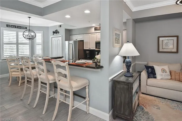 Kitchen with ornamental molding, a kitchen breakfast bar, recessed lighting, dark countertops, and appliances with stainless steel finishes