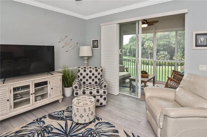 Living room with crown molding, ceiling fan, and wood finished floors