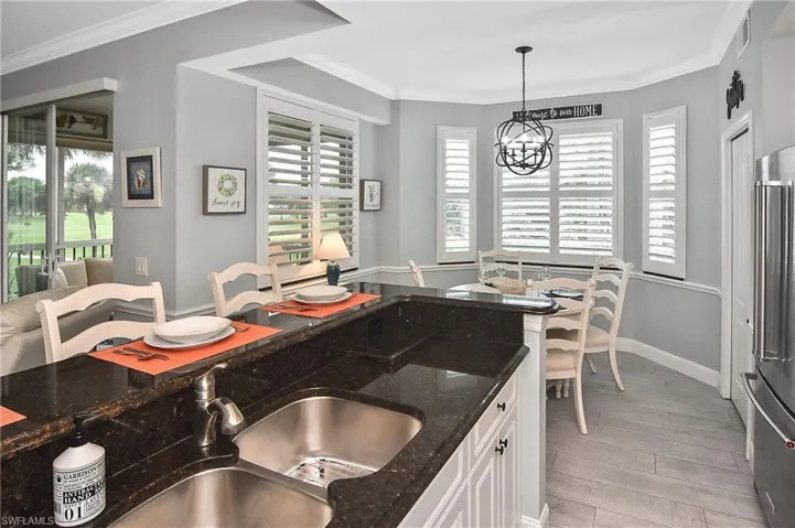 Kitchen featuring ornamental molding, light wood finished floors, high end fridge, plenty of natural light, and hanging light fixtures