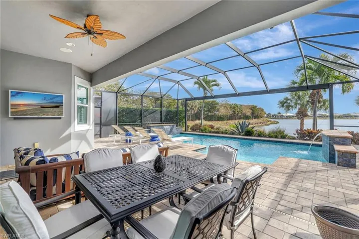 Outdoor pool featuring dual waterfalls,patio area, a lanai, a water view, and outdoor dining space