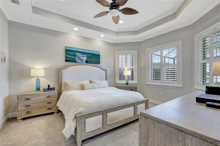 Owners Suite featuring crown molding, ceiling fan, light colored carpet, and recessed lighting with beautiful views to the pool and out to the lake