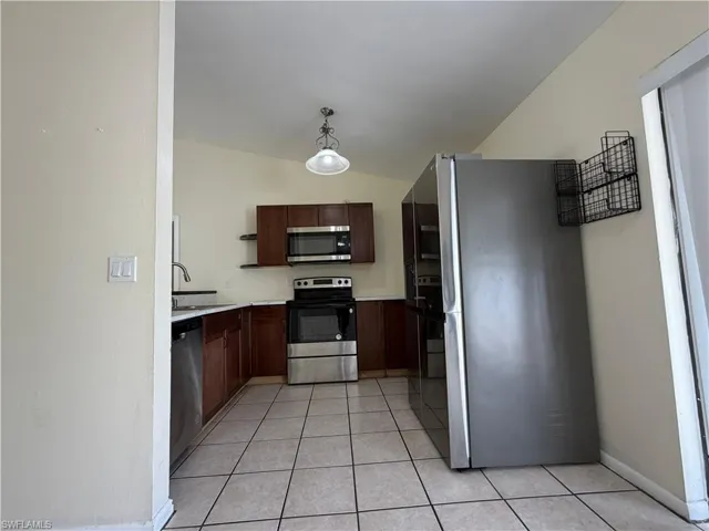 The kitchen features dark wood cabinetry, stainless steel appliances, and a tiled floor