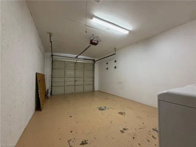 The garage features a paneled overhead door, an automatic garage door opener, and overhead fluorescent lighting