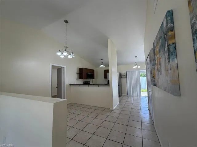 Open concept living area featuring vaulted ceilings, tile flooring, and pendant lighting