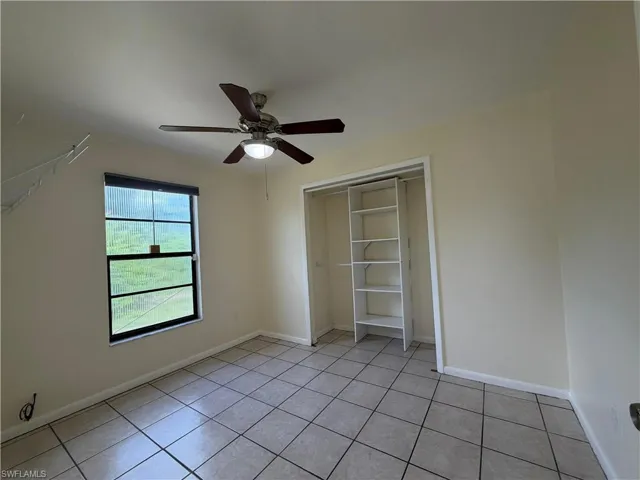 Room featuring light-colored walls, a ceiling fan with light fixture, and tiled flooring