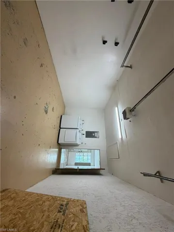 Utility space featuring a stacked washer and dryer, an electrical panel, and a wall-mounted light fixture