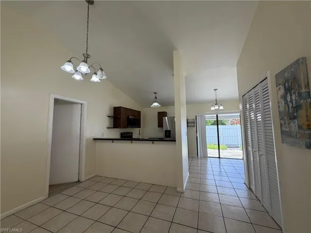 The property features vaulted ceilings, tile flooring, and a kitchen area with dark cabinetry