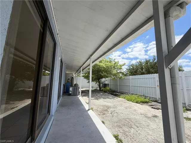 The property features an outdoor patio with a covered area, a concrete surface, and a white fence