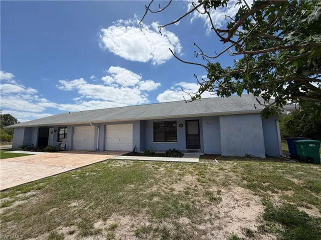 This property features a light blue exterior, a gray roof, and two white garage doors