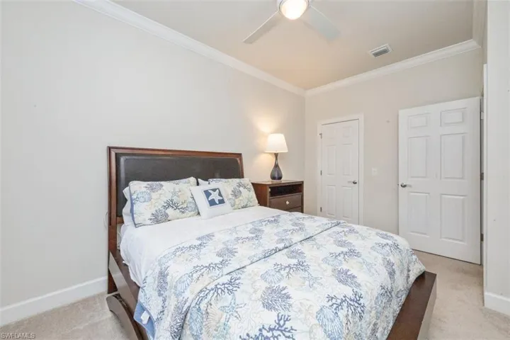 Bedroom with light carpet, ornamental molding, and a ceiling fan
