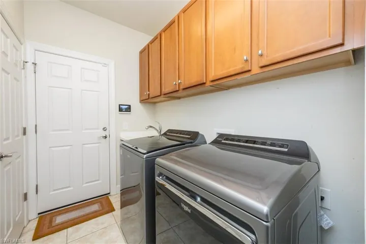 Laundry room with light tile patterned floors, washer and dryer, and cabinet space