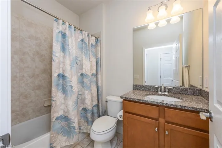 Full bath with vanity, shower / bathtub combination with curtain, and light tile patterned flooring
