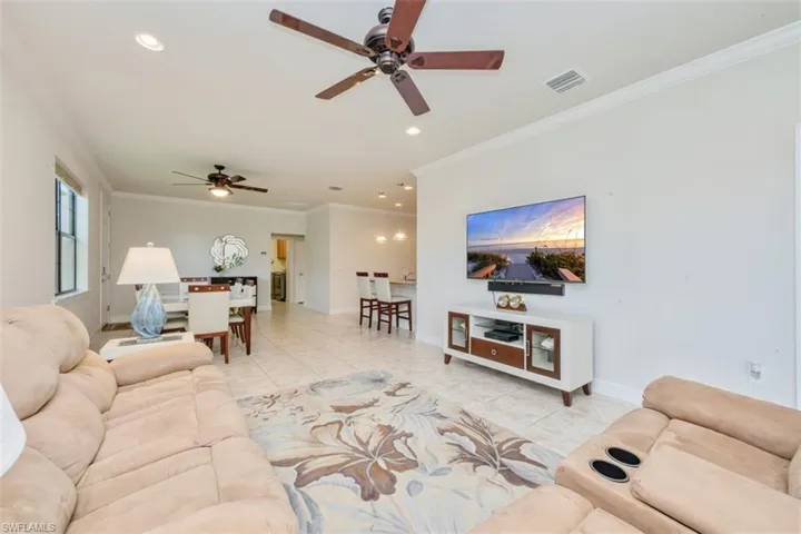 Living room with crown molding, ceiling fan, light tile patterned floors, and recessed lighting