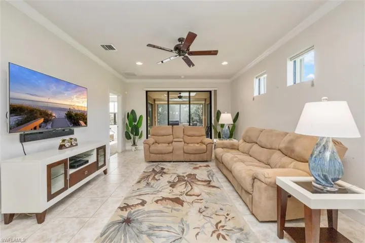 Living area with ornamental molding, ceiling fan, light tile patterned floors, and recessed lighting