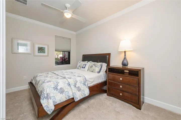 Carpeted bedroom featuring crown molding and a ceiling fan
