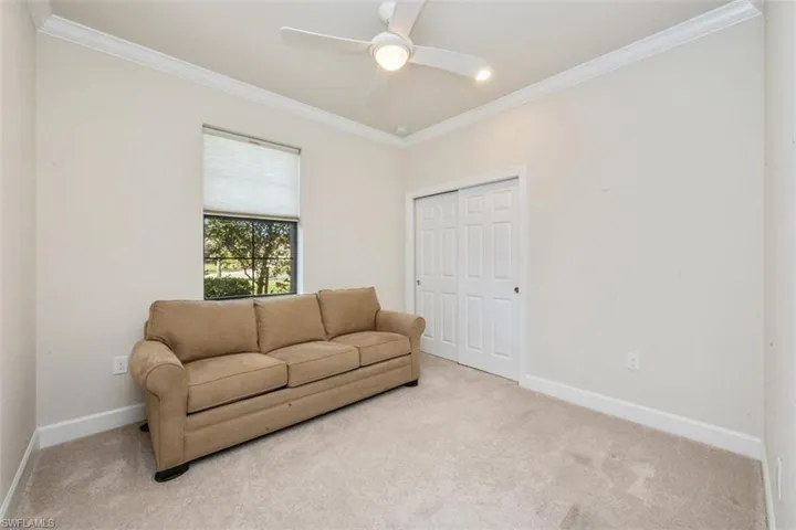 Carpeted living room featuring ornamental molding and ceiling fan