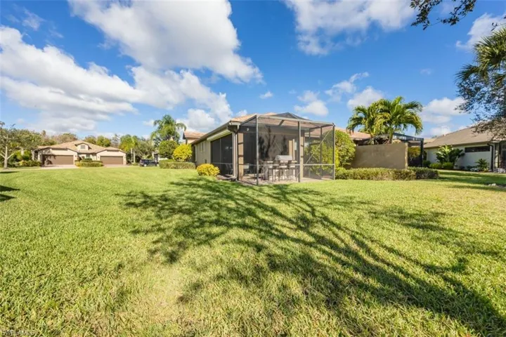View of grassy yard featuring glass enclosure and a sunroom