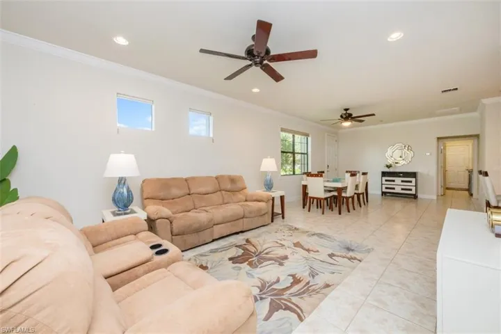 Living area with crown molding, recessed lighting, light tile patterned flooring, and a ceiling fan