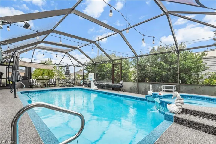 View of swimming pool featuring a patio area, a pool with connected hot tub, and a lanai