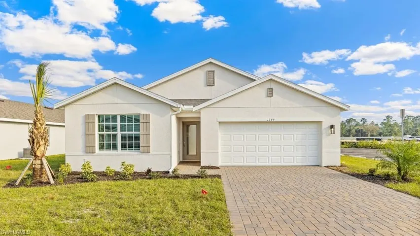 Model home. Ranch-style home featuring stucco siding, decorative driveway, a front yard, and an attached garage