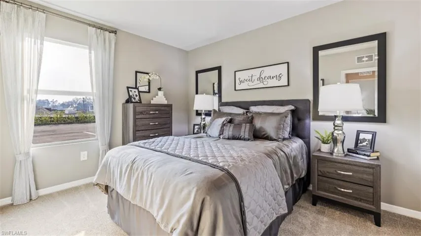 Model home. Bedroom with baseboards and light colored carpet