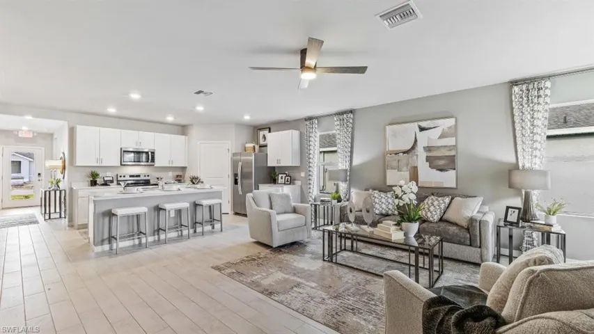 Model home. Living room with a ceiling fan, light wood finished floors, and recessed lighting