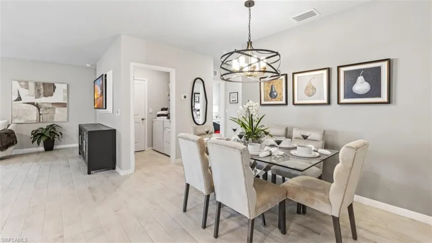 Model home. Dining room featuring light wood finished floors, suspended lighting, and washer / clothes dryer