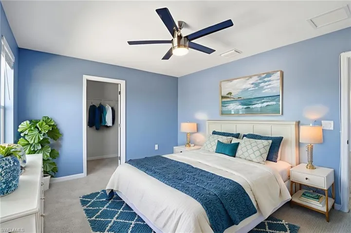 Bedroom with light colored carpet, a spacious closet, ceiling fan