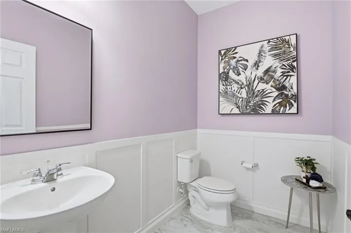 Powder-room  featuring wainscoting, a decorative wall, and light marble finish floors