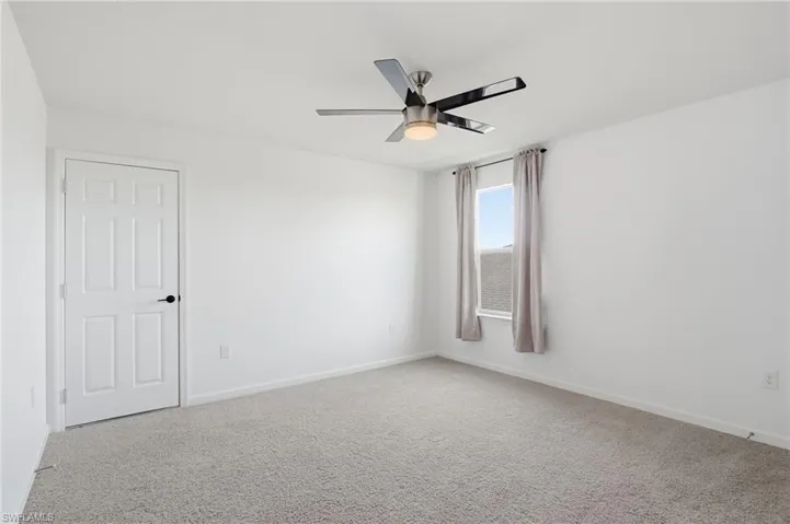 Empty room featuring carpet flooring and a ceiling fan