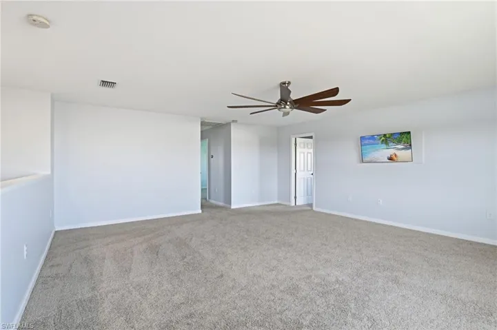 Empty room featuring carpet floors and a ceiling fan