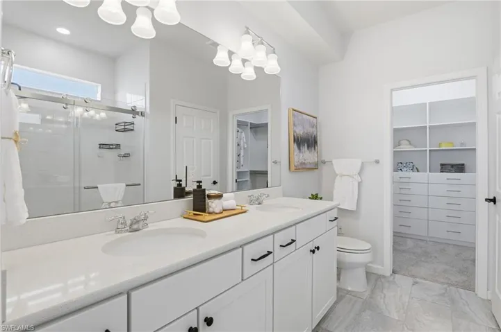 Full bathroom with a spacious closet, double vanity, and a shower stall