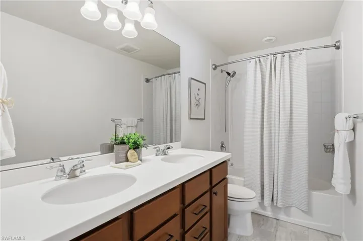 Bathroom with shower / bath combo with shower curtain, double vanity, and a chandelier