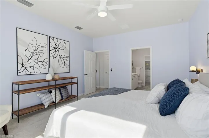 Carpeted bedroom featuring ensuite bathroom and ceiling fan