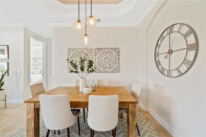 Dining area featuring tile patterned flooring, a raised ceiling, and ornamental molding