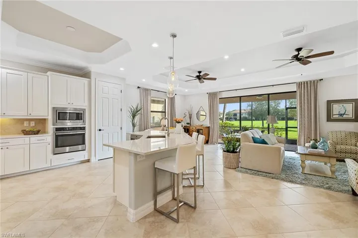 Kitchen with pendant lighting, stainless steel appliances, a raised ceiling, and ceiling fan