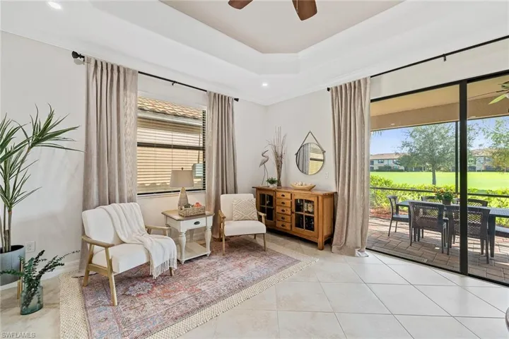 Sitting room featuring tile patterned flooring, ceiling fan, and a raised ceiling